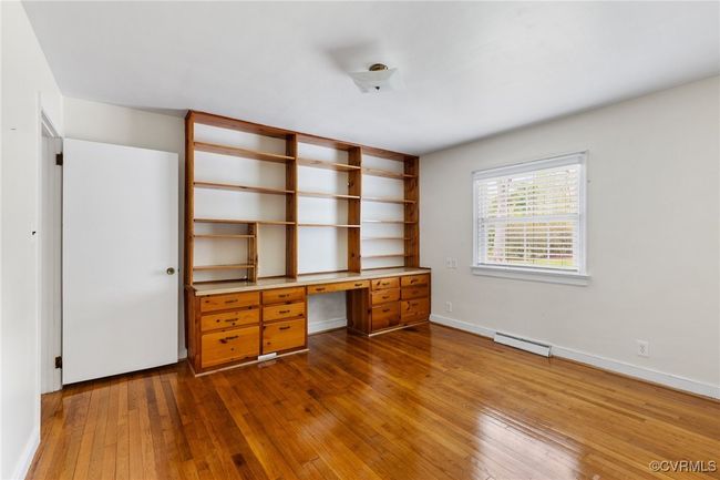 Unfurnished office with a baseboard radiator, baseboards, dark wood finished floors, and built in study area | Image 16