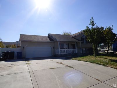 View of front of home featuring a mountain view, covered porch, a front yard, and a garage | Image 1