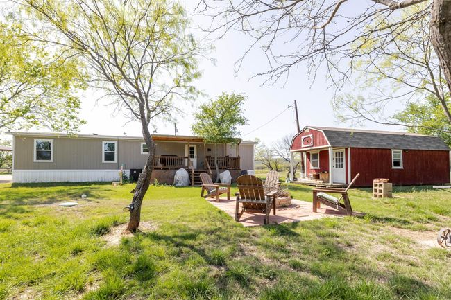 Back of house with a gambrel roof, an outbuilding, a yard, a patio area, and a fire pit | Image 28