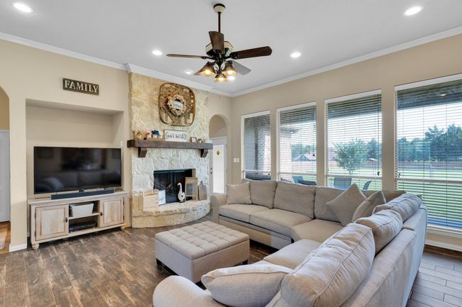 Living area with arched walkways, a ceiling fan, dark wood-type flooring, ornamental molding, and recessed lighting | Image 4