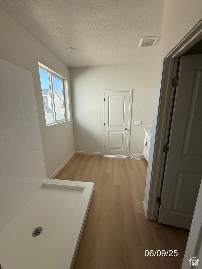 Hallway featuring light wood-type flooring, a textured ceiling, and baseboards | Image 6