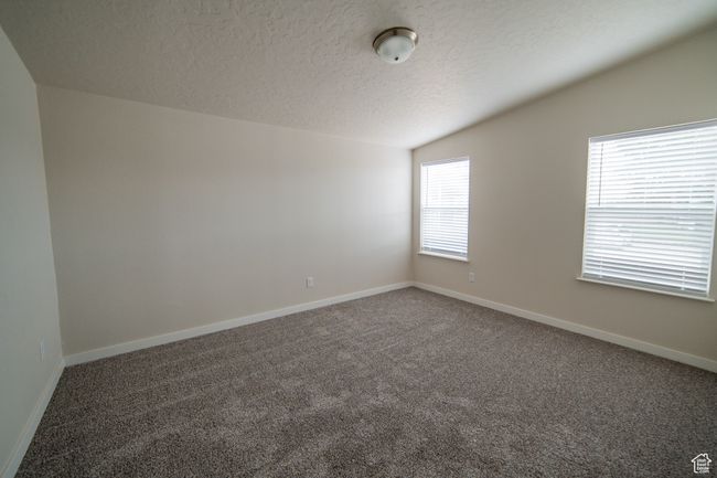 Carpeted empty room featuring vaulted ceiling, baseboards, and a textured ceiling | Image 36
