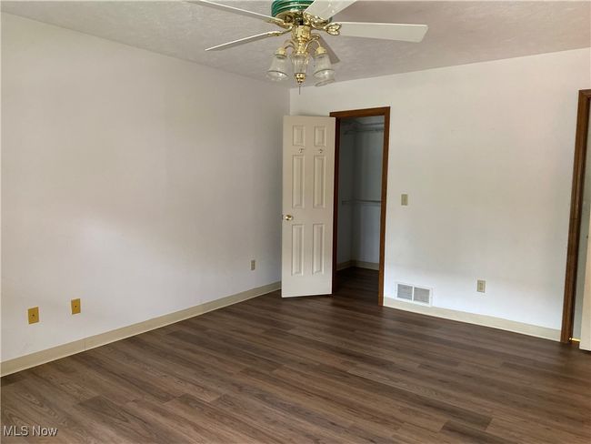 Empty room with ceiling fan, dark wood-style flooring, and baseboards | Image 20