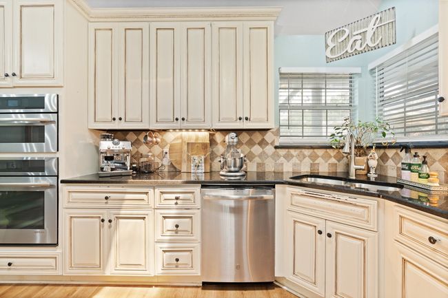 Kitchen with cream cabinets, stainless steel appliances, backsplash, and dark stone counters | Image 9
