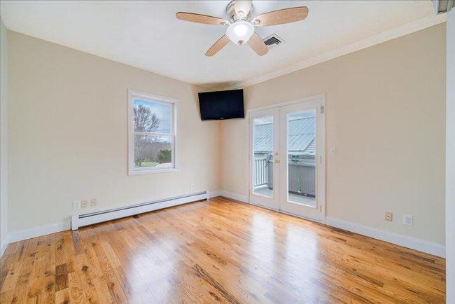 Empty room featuring visible vents, a healthy amount of sunlight, wood finished floors, and baseboard heating | Image 16