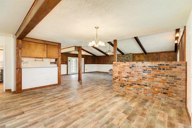 View of Dining Area toward Living Area. The wood-look tile flooring is just gorgeous, and the smart brick accent wall gives a bit of separation between the two spaces. | Image 24