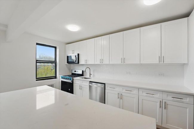 Kitchen with white cabinets, stainless steel appliances, and a sink | Image 8