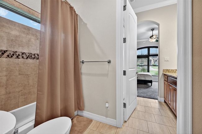 Bathroom featuring tile patterned flooring, vanity, shower / bathtub combination with curtain, ornamental molding, and a ceiling fan | Image 30