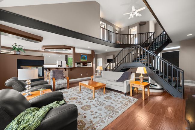 Living area featuring stairway, high vaulted ceiling, baseboards, and wood finished floors | Image 9