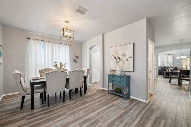 Dining space featuring a chandelier, arched walkways, wood finished floors, and visible vents | Image 10