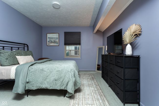 bedroom with carpet flooring, vaulted ceiling, and a textured ceiling | Image 18