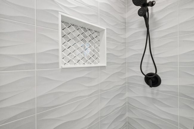 Notice the floor to ceiling dimensional modern tile-surround, the large stone niche, the mosaic shower flooring and the frameless double sliding shower glass door. | Image 21