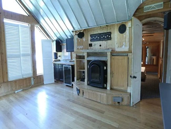 Unfurnished living room featuring vaulted ceiling, light wood-style flooring, wood walls, and arched walkways | Image 8
