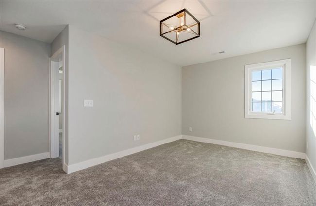 Empty room with carpet floors, a chandelier, baseboards, and a smoke detector | Image 18