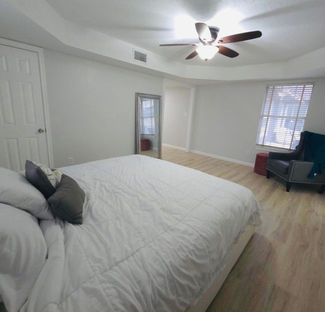 Bedroom featuring wood finished floors, a tray ceiling, and ceiling fan | Image 14