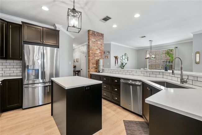 The kitchen is well-appointed with a generous amount of cabinetry for storage and ample counter space for preparing meals, including a center island. | Image 13