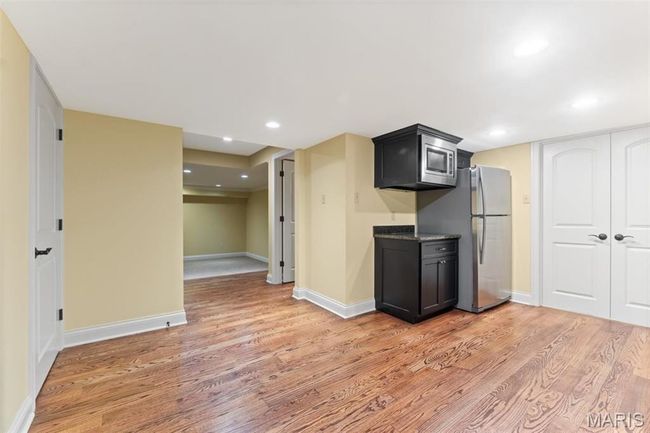 Kitchen featuring light wood finished floors, stainless steel appliances, dark cabinetry, and recessed lighting | Image 48