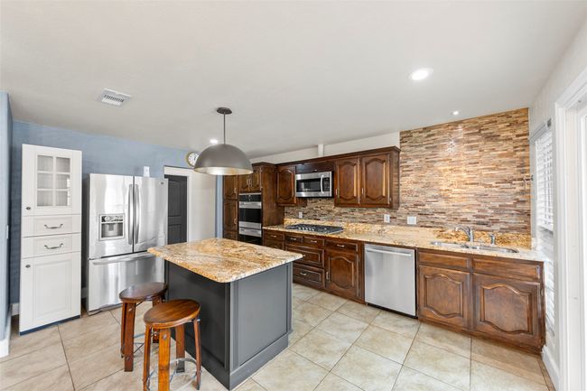Kitchen with tasteful backsplash, stainless steel appliances, light tile patterned floors, a sink, and visible vents | Image 10