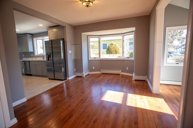Unfurnished dining area with baseboard heating, a wealth of natural light, sink, and light hardwood / wood-style flooring | Image 5