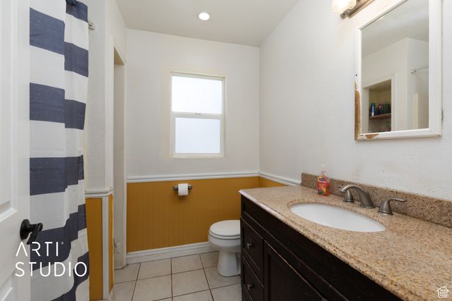 Full bath with vanity, toilet, wainscoting, tile patterned floors, and baseboards | Image 46