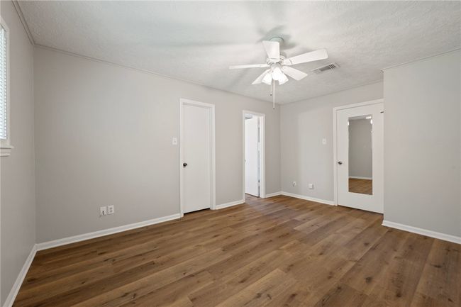 Spare room with wood finished floors, ceiling fan, baseboards, and a textured ceiling | Image 12