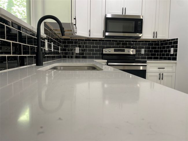 Kitchen with appliances with stainless steel finishes, white cabinets, a sink, and tasteful backsplash | Image 16
