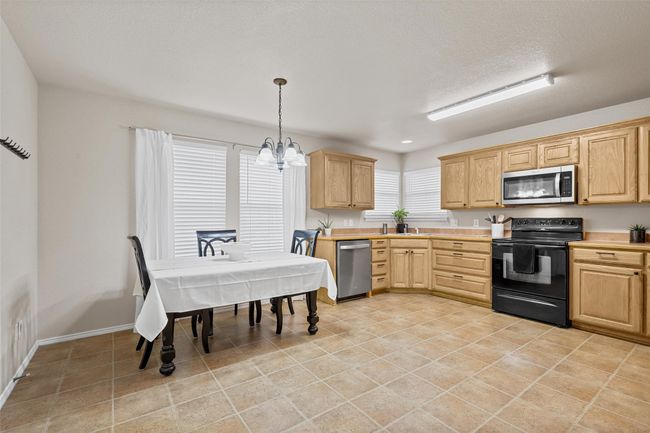 Kitchen with stainless steel appliances, light countertops, an inviting chandelier, and light brown cabinetry | Image 11