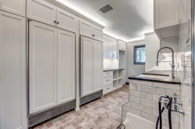 Kitchen with a textured ceiling, white cabinetry, and dark countertops | Image 21