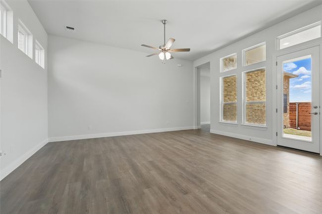 Empty room with visible vents, baseboards, wood finished floors, and a ceiling fan | Image 12