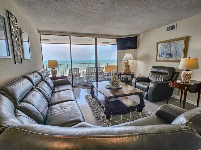 Living area featuring a textured ceiling, a wall of windows, and tile patterned floors | Image 9