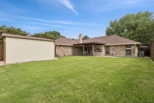 Back of property featuring a chimney, a fenced backyard, brick siding, a patio, and a shingled roof | Image 30