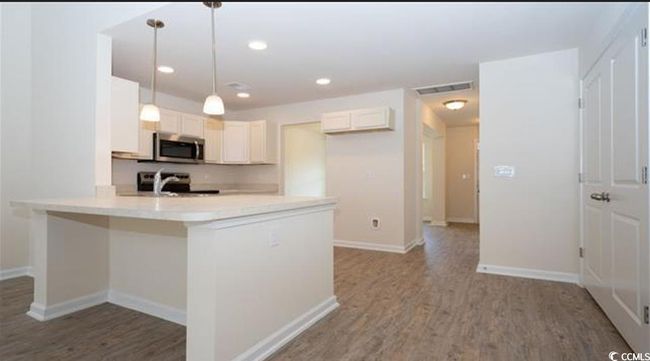Kitchen featuring visible vents, light countertops, appliances with stainless steel finishes, a peninsula, and wood finished floors | Image 11