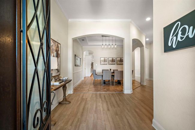 Step into the welcoming entryway featuring a covered archway that flows effortlessly into entertainment areas. The formal dining room, showcasing abundant natural light and tile flooring, offers ample space for hosting with its open layout and sophisticated elegance. This area sets the tone for the home's graceful interior design. | Image 10