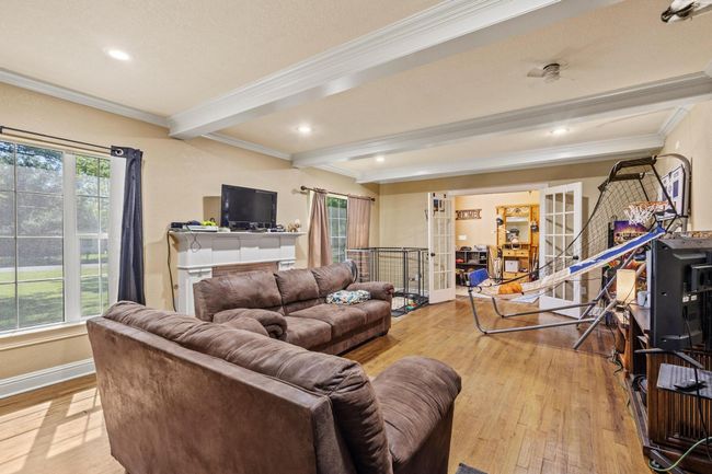 Living room with beamed ceiling, light wood-type flooring, and crown molding | Image 15