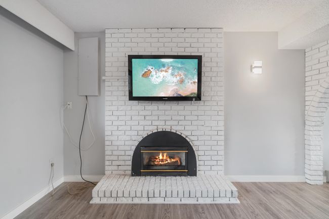 Room details with a brick fireplace, a textured ceiling, baseboards, and wood finished floors | Image 29