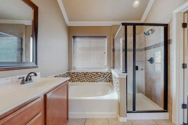 Bathroom with a bath, vanity, a stall shower, crown molding, and tile patterned floors | Image 10