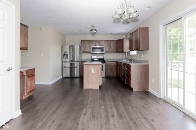 kitchen featuring stainless steel appliances, a chandelier, dark wood finished floors, light countertops, and a center island | Image 14