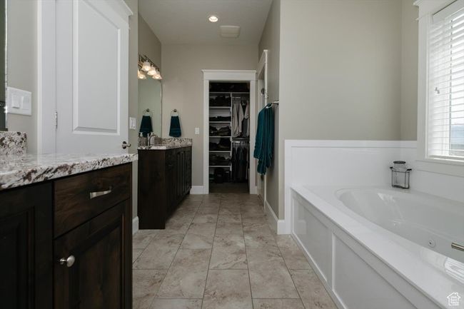 Bathroom featuring a walk in closet, a jetted tub, and vanity | Image 45