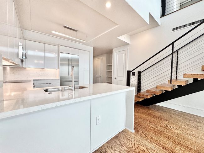 Kitchen with high end fridge, light wood-style flooring, light stone counters, a sink, and a peninsula | Image 24