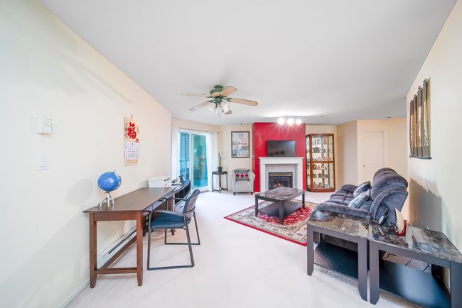 Living room featuring a ceiling fan, a fireplace, light carpet, and baseboards | Image 19