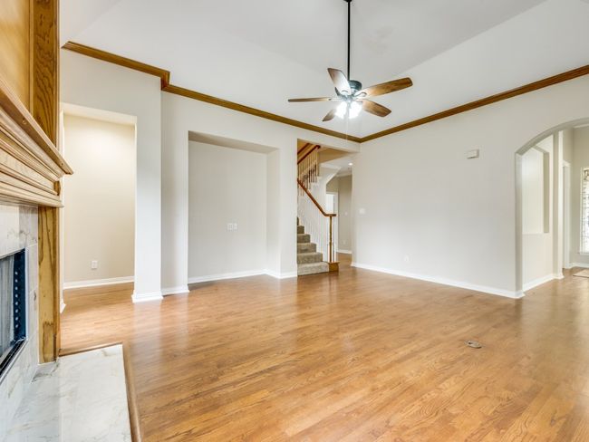 Family room featuring arched walkways, gas fireplace with gas logs and gas starter, hardwood floors, and niche for a large flat screen tv. The primary bedroom is located to the left of the niche. The secondary bedrooms and bath are to the right of the stairs. | Image 11