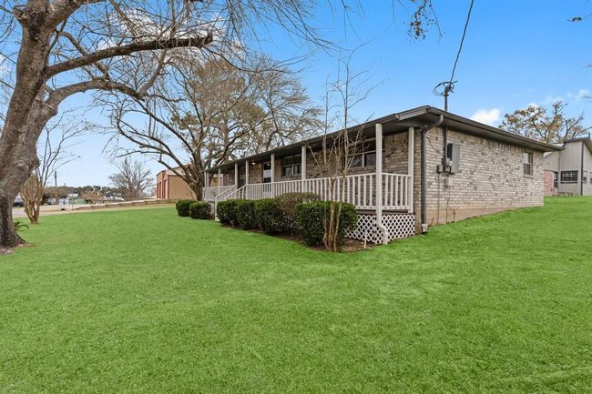 Single-story brick home with a welcoming wrap-around porch, nestled on a spacious, well-maintained lawn. | Image 5