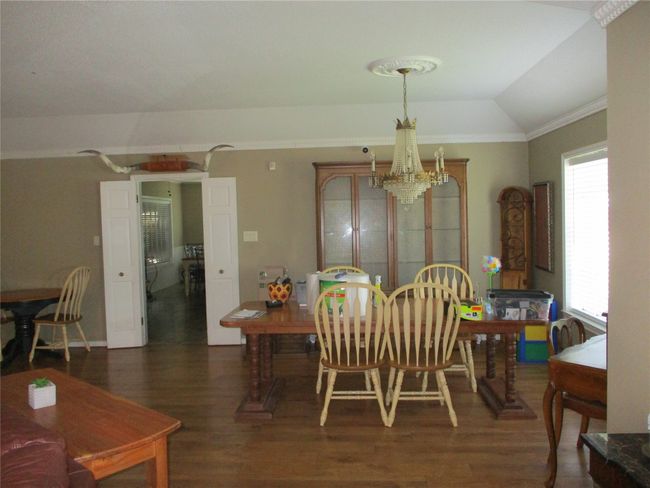 Dining area featuring dark hardwood / wood-style floors, crown molding, vaulted ceiling, and a chandelier | Image 22