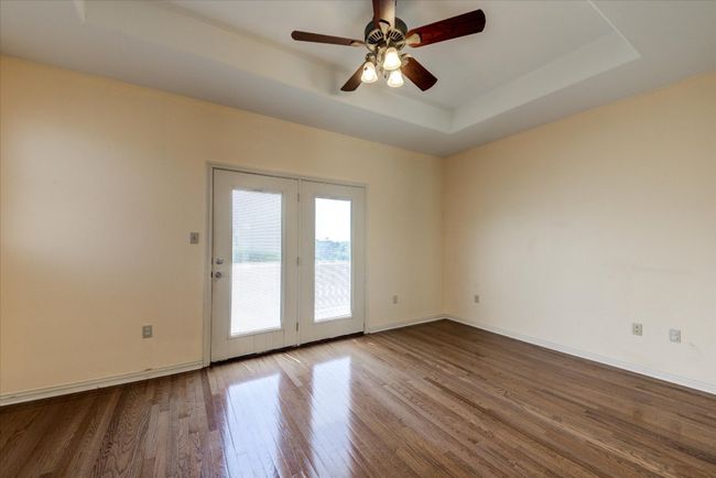 Bedroom 4. Upstairs bedroom with tray ceiling, dual doors leading to a deck that overlooks the pool and backyard acreage. | Image 20