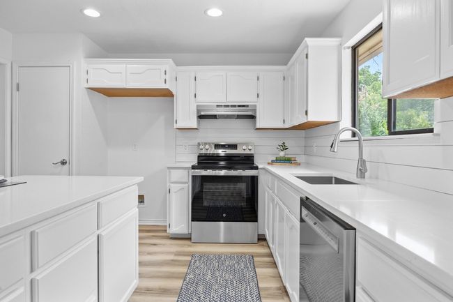 Kitchen with stainless steel appliances, recessed lighting, under cabinet range hood, white cabinets, and tasteful backsplash | Image 11