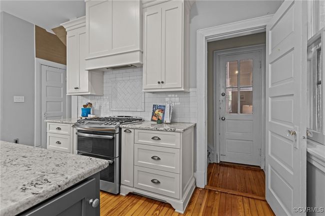 Kitchen with decorative backsplash, range with two ovens, and white cabinets | Image 16