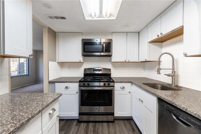 Kitchen with white cabinetry, stainless steel appliances, visible vents, and a sink | Image 10