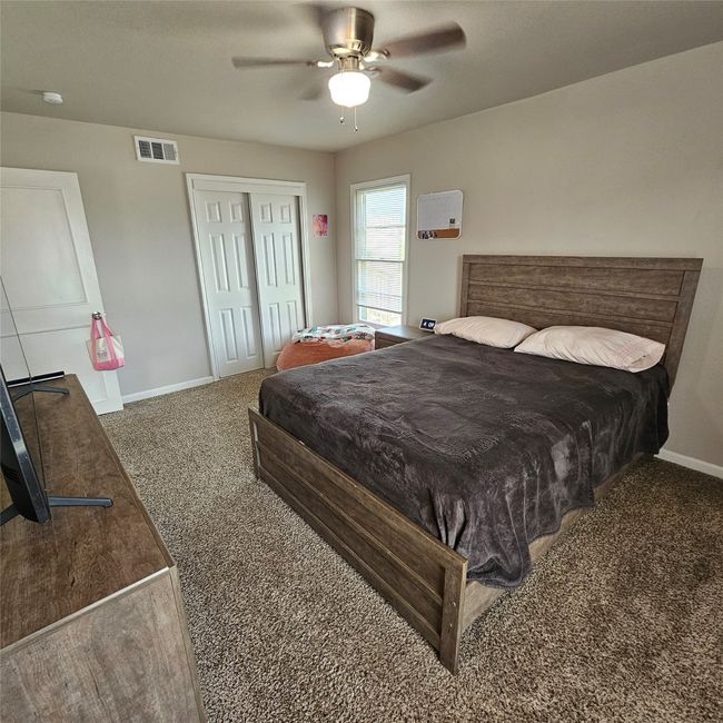 Carpeted bedroom with ample space featuring baseboards, a closet, and ceiling fan. | Image 19