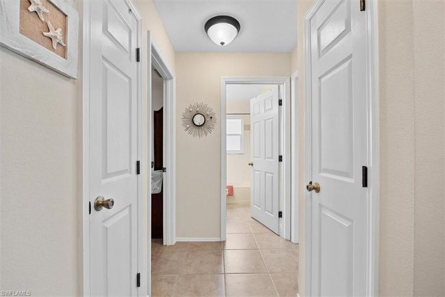 Hall featuring light tile patterned flooring and baseboards | Image 7
