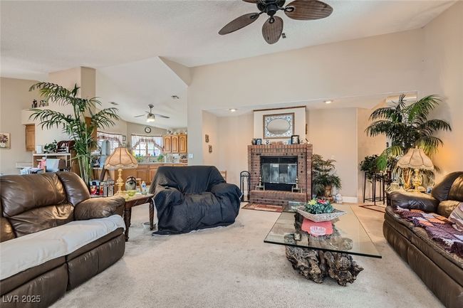 Living area with vaulted ceiling, carpet floors, a fireplace, and a ceiling fan | Image 7